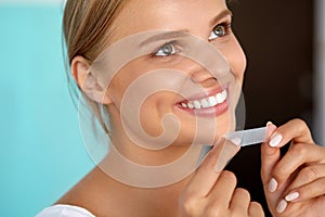 Woman With Healthy White Teeth Using Teeth Whitening Strip