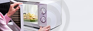 Woman Heating Food In Microwave