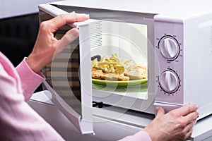 Woman Heating Food In Microwave photo