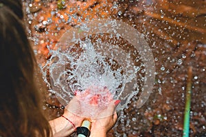 Woman heaving fun with hosepipe splashing water