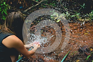 Woman heaving fun with hosepipe splashing water