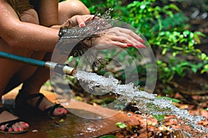 Woman heaving fun with hosepipe splashing water