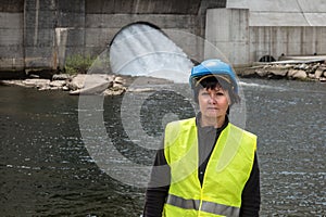 Woman in a helmet against the backdrop of hydroelectric turbines