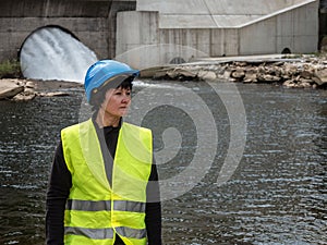 Woman in a helmet against the backdrop of hydroelectric turbines