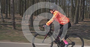 Woman in helmet is pedaling on road bike. Female cycling. Girl riding on bicycle. Triathlon concept