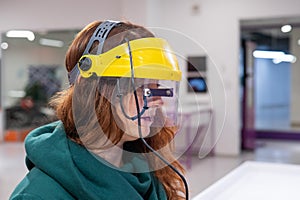 A woman in a helmet synchronizing her gaze and the movement of a computer mouse.