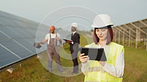 Woman in helmet using digital tablet for work on solar station. African american business and indian technician talking