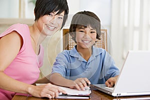 Woman helping boy with laptop doing homework