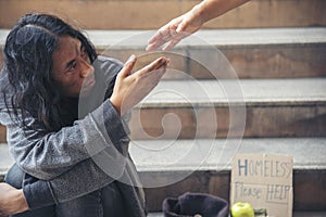 Woman helping hands to homeless people poverty beggar man holding hands asking for money job and hoping help in helpless dirty photo