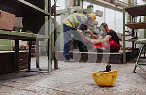 Woman is helping her colleague after accident in factory. First aid support on workplace concept.