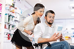 Woman helping her disabled husband to choose pharmaceuticals in drugstore