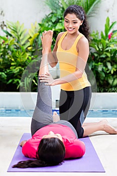 Woman helping her friend to raise leg in abdominal workout