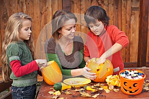 Woman helping kids to carve jack-o-lanterns