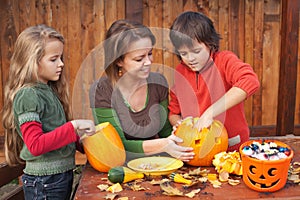 Woman helping kids to carve jack-o-lanterns photo