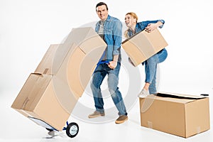 Woman helping man holding trolley cart with cardboard boxes