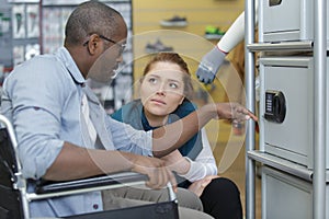 woman helping man in wheelchair next to sports locker