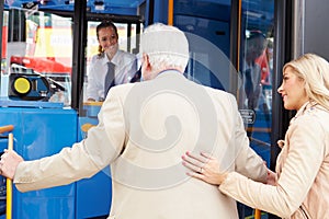 Woman Helping Senior Man To Board Bus