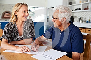 Woman Helping Senior Man To Complete Last Will And Testament At Home