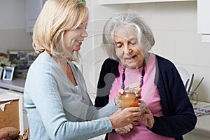 Woman Helping Senior Neighbor To Remove Jar Lid