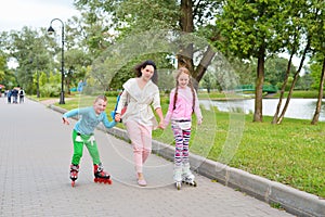 Woman helps children to roller skate in the Park