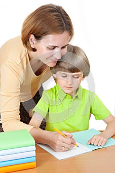 A woman helps first graders how to write in a notebook