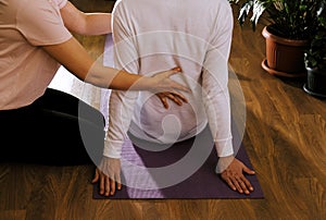 Woman helps  man to do exercises for back pain. Physical therapy concept