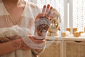 Woman with henna tattoo on hands indoors, closeup. Traditional mehndi ornament
