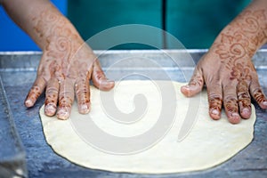 Woman with henna tattoos on hands preparing pancakes. Msemen Round flatbread dough prepared on the grill, Marrakech, Morocco Essa photo