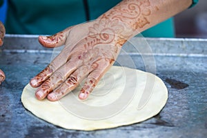 Woman with henna tattoos on hands preparing pancakes. Msemen Round flatbread dough prepared on the grill, Marrakech, Morocco Essa photo