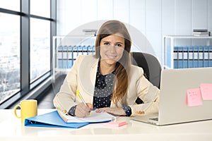 Woman on her 30s at office working at laptop computer desk taking notes
