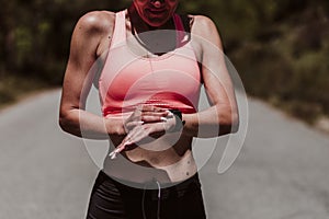 Woman in her 40s making exercise outdoors in a sunny day and checking smart watch. Healthy life and sport lifestyle concept