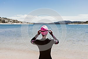 Woman in her 40s wearing a neoprene and waiting to swim in the lake. Triathlon concept
