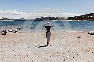 Woman in her 40s wearing a neoprene and waiting to swim in the lake. Triathlon concept