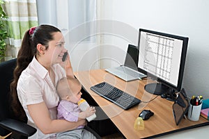 Woman With Her Baby Talking On Mobile Phone