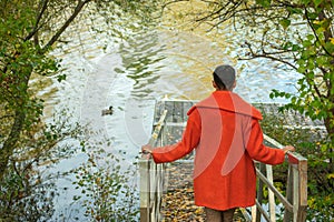 Woman on her back with orange coat going down to the river pier