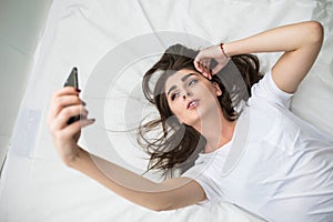 Woman on her bed taking selfy