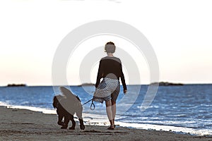Woman with her big inseparable dog walking by the sea