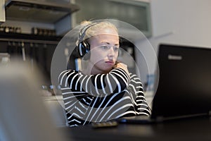 Adult woman in her casual home clothing working and studying remotely from her small flat late at night. photo