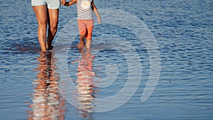 A woman and her child wade across a flooded pond. Their silhouettes are reflected in the water. Copy space.
