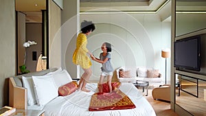 Woman and her daughter jumping on bed