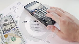 a woman at her desk counts the cost of utility bills, rising prices for water and heating