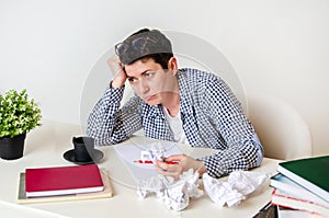 Woman at her desk with laptop and crumpled sheets of paper. Creative crisis, sadness, despair