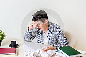 Woman at her desk with laptop and crumpled sheets of paper. Creative crisis, sadness, despair