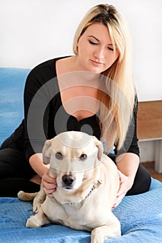 Woman with her dog in bed at home, relaxing in bedroom. Beautiful girl is playing, together and petting with dog in bed.
