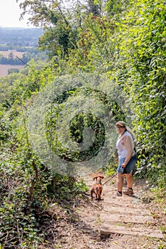 Woman with her dog down stairs down slope, turned and looking at camera