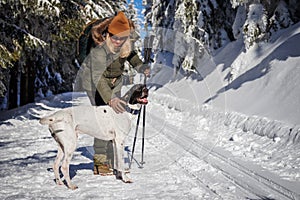 Woman with her dog hiking in winter forest