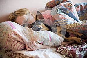 Una mujer a su el perro durmiendo en una cama 