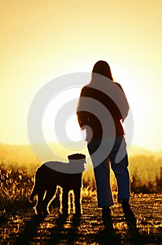 Woman & her dog walking in together in sunset