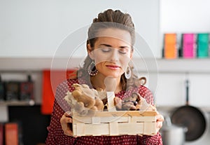 Woman with her eyes closed smelling basket of fresh mushrooms