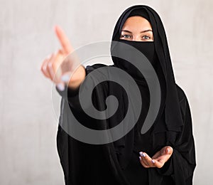 woman with her face covered by burka points her hand to side